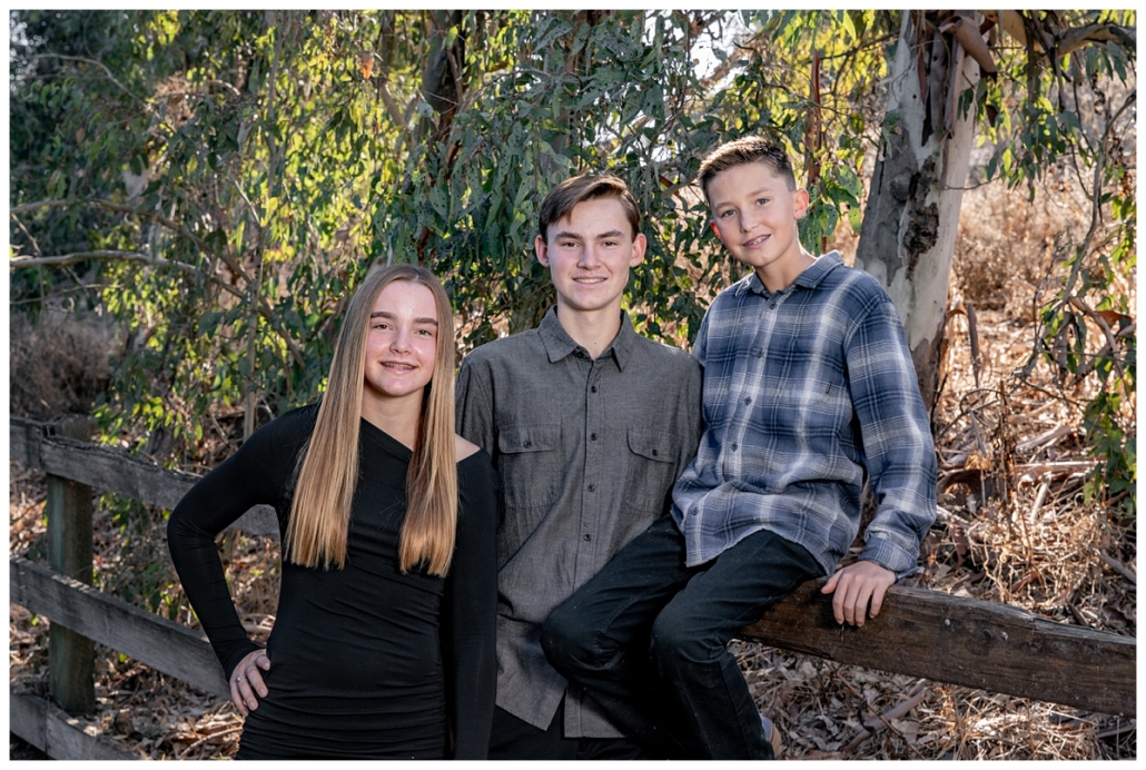 Siblings leaning on a fence for family picture in Orange County