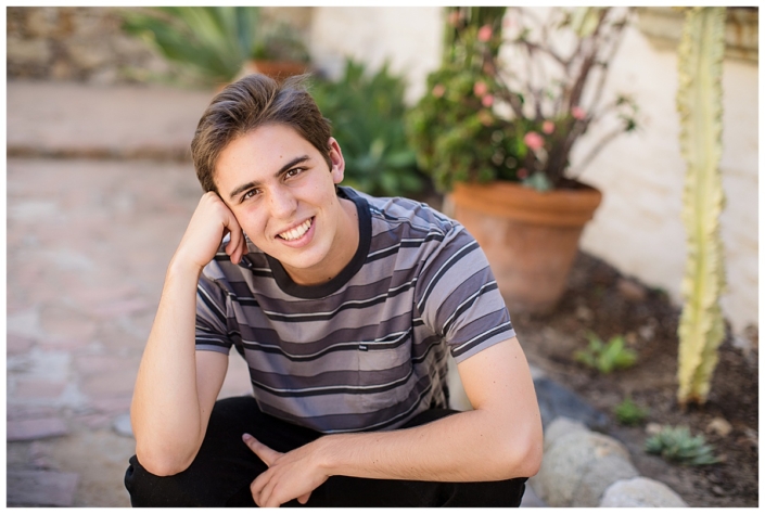 High School senior guy squatting pose in the Mission in San Juan Capistrano