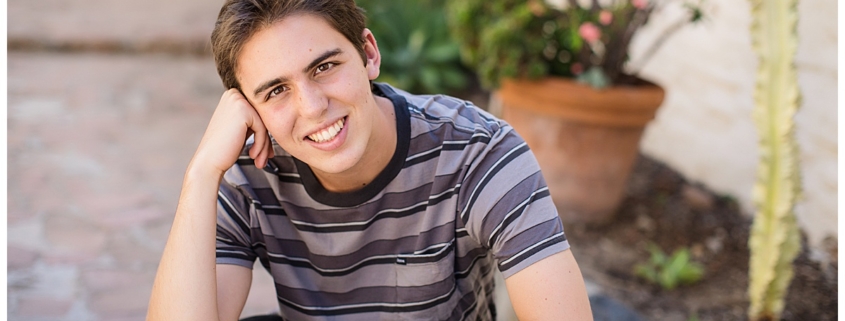 High School senior guy squatting pose in the Mission in San Juan Capistrano