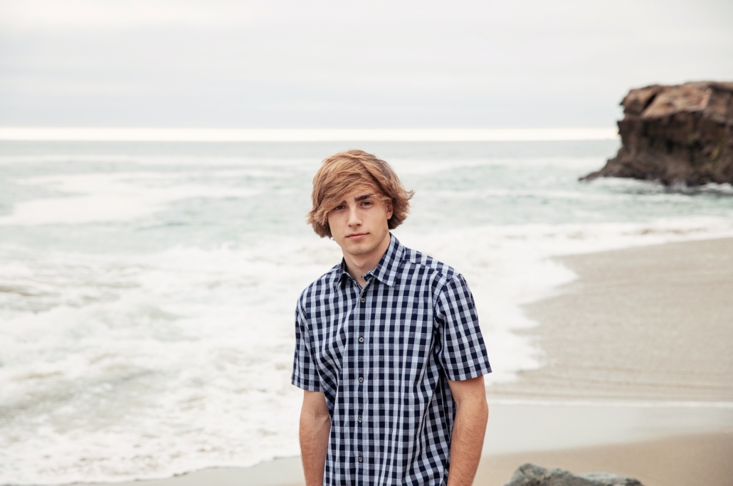 High School senior guy at the beach with an ocean background.