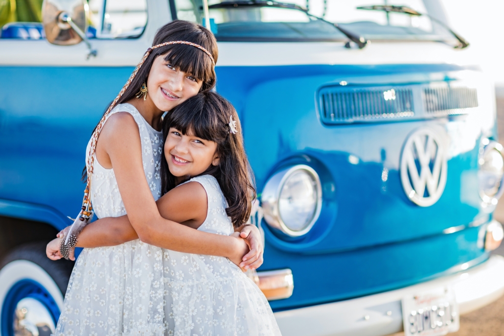 Sibling sisters hugging in front of a vintage VW van in Orange County 