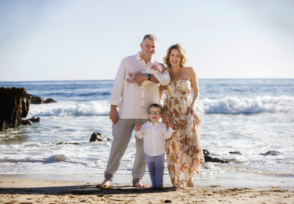 A family photography session in Laguna Beach. All the family members are dressed in creams and neutral tones.