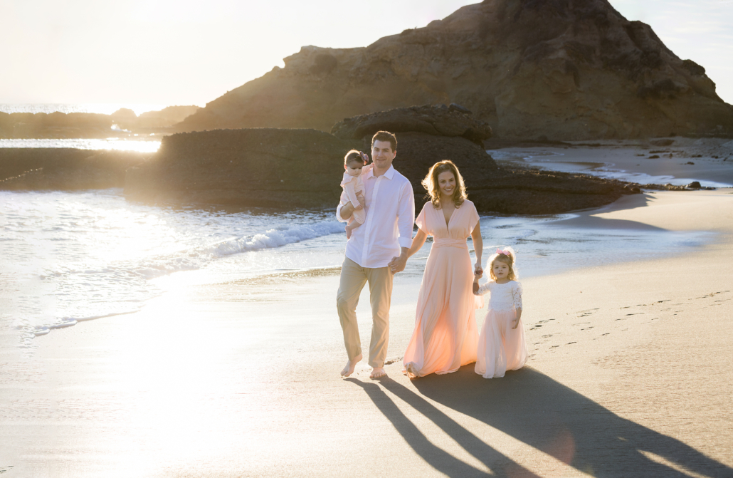 Young family wearing pastel colors at their sunset family photoshoot in Laguna Beach
