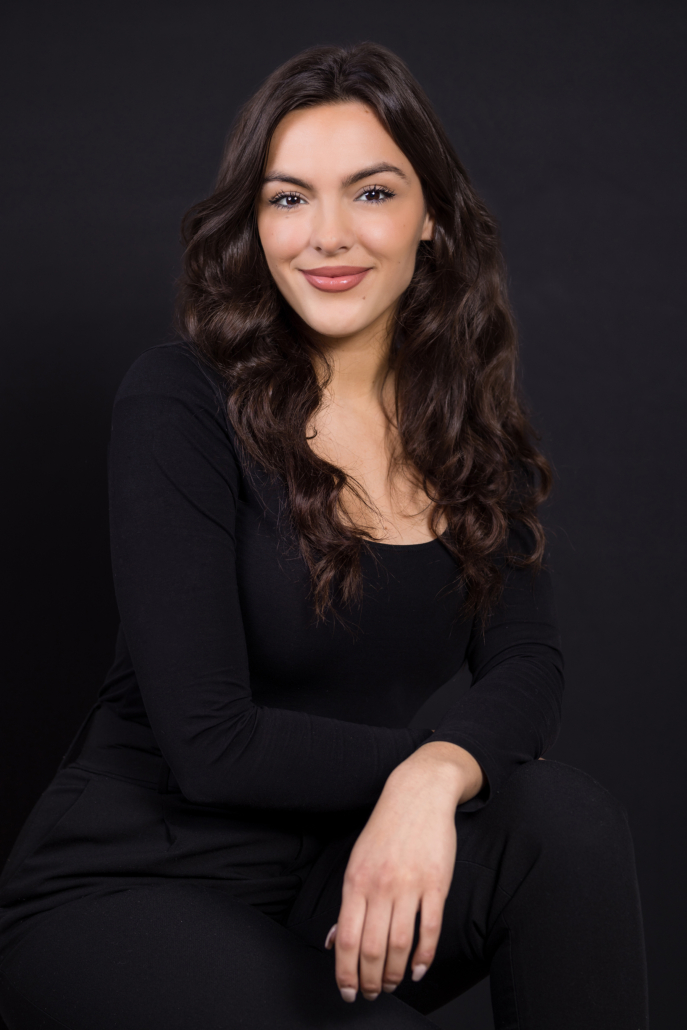 female executive photoshoot all in black with a black background and outfit. Bold makeup makes this headshot stand out.