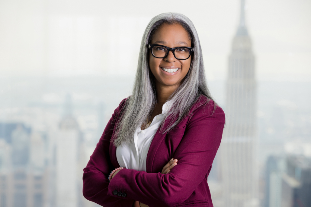 Female executive wearing a bold solid blazer in rasberry pink with statement glasses. This is a perfect example of what to wear female executive to a headshot session.