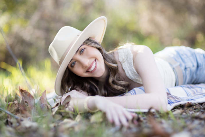 An image of what to wear to a senior session including accessories such as a hat and chunky jewelry. Image taken in Laguna Canyon in a field.
