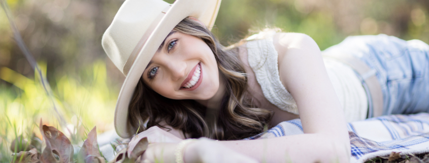 An image of what to wear to a senior session including accessories such as a hat and chunky jewelry. Image taken in Laguna Canyon in a field.