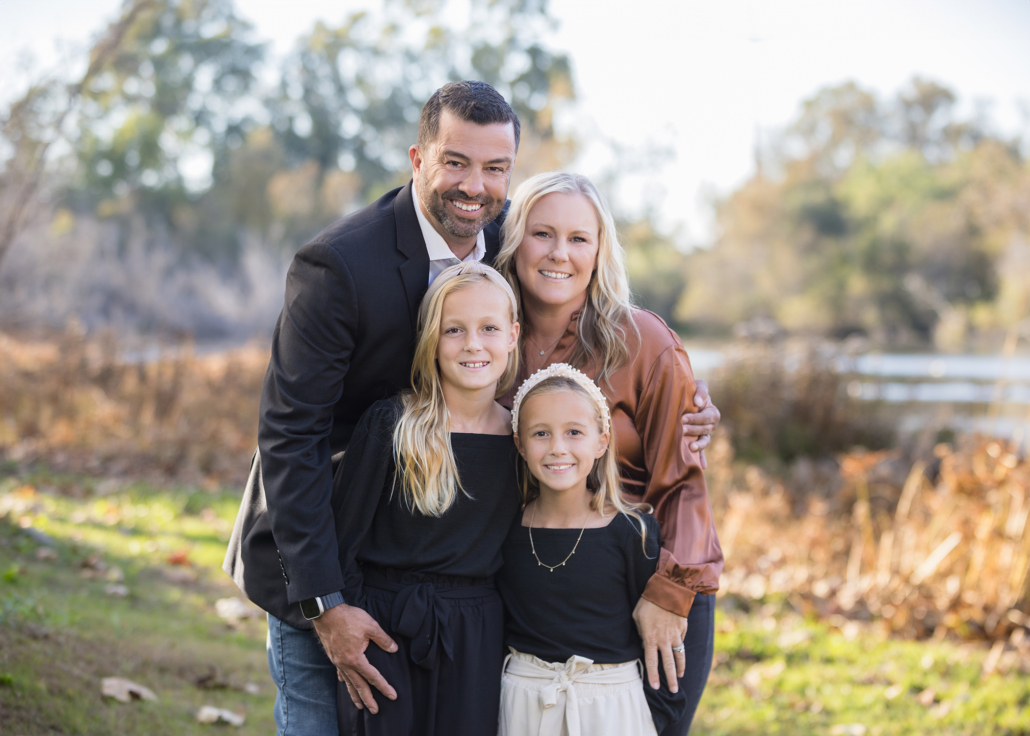 Family of four getting portraits done in front of the lake in Huntington Beach Central Park