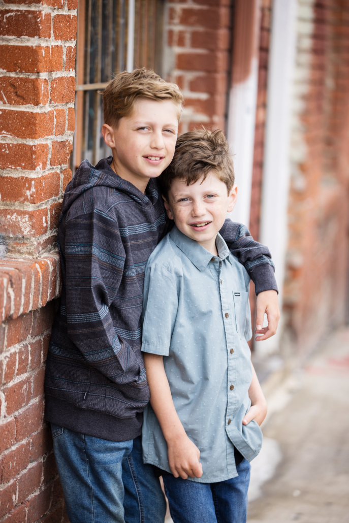 Two brother getting their portrait taken in the brick alley ways in Orange County CA