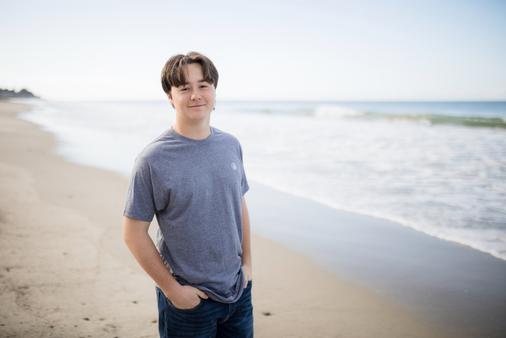 High school senior standing by the ocean at San Clemente Beach during his photoshoot