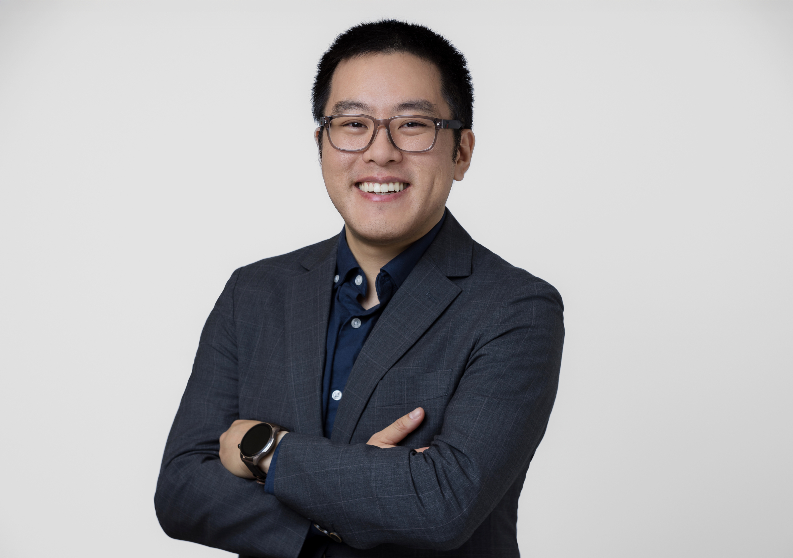 Smiling male professional in glasses and grey suit against a clean white background