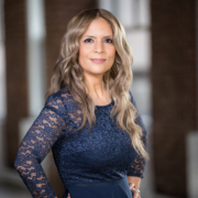 Professional woman in navy lace dress posing for a headshot in a modern NYC office