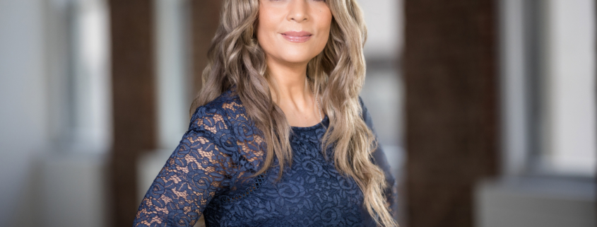 Professional woman in navy lace dress posing for a headshot in a modern NYC office