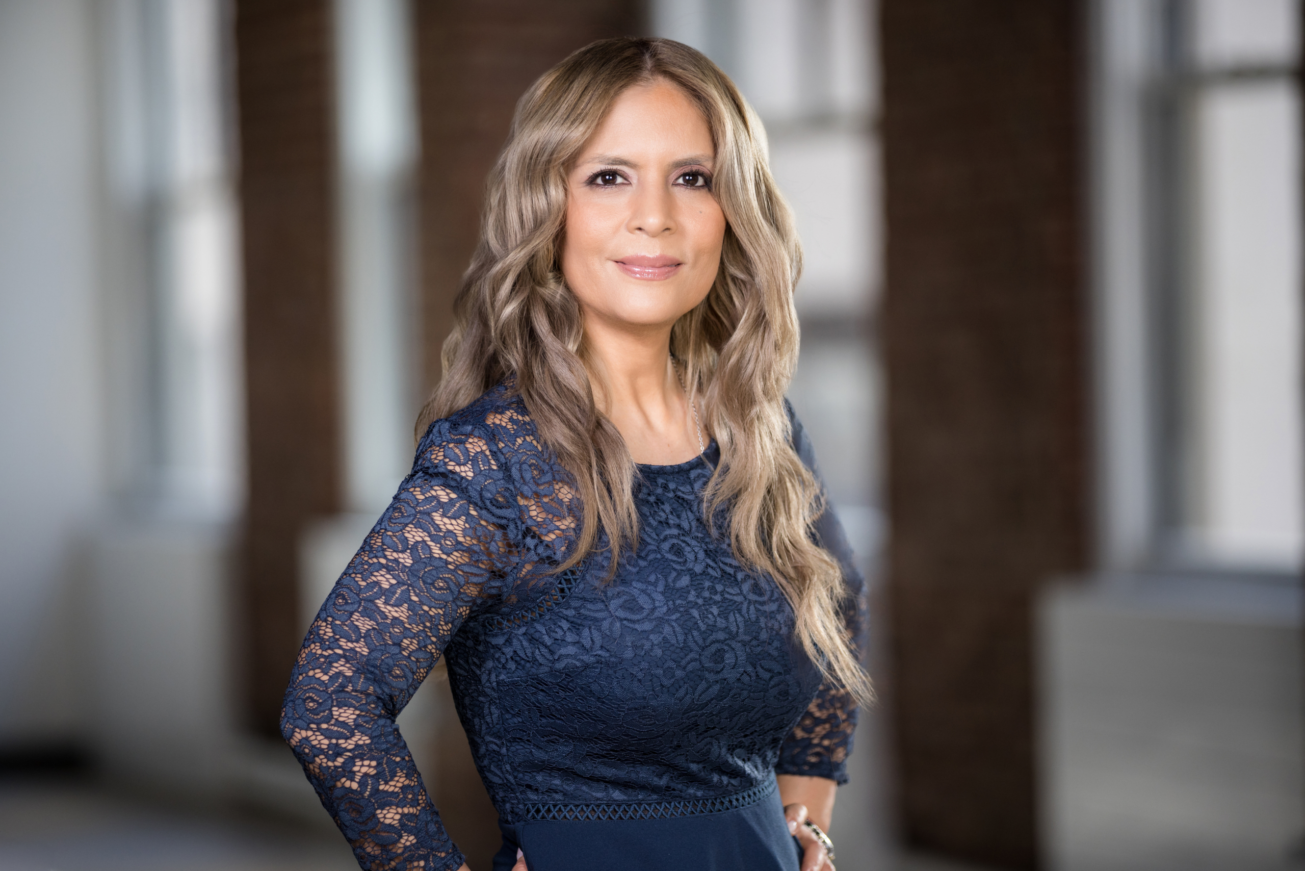  Professional woman in navy lace dress posing for a headshot in a modern NYC office