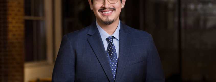 Business professional in navy plaid suit and polka-dot tie smiling in modern office