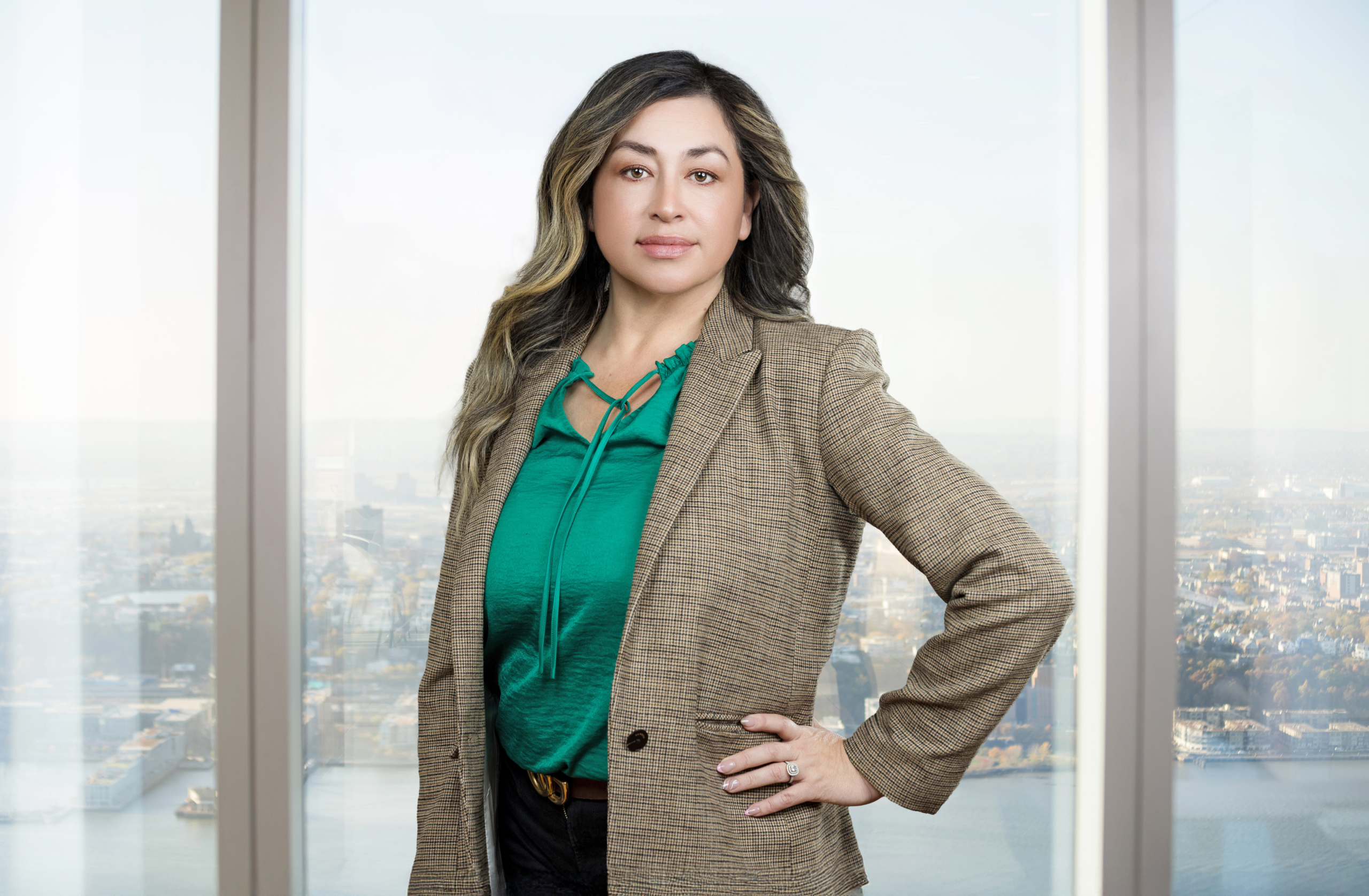Confident businesswoman in green blouse with NYC skyline background. 
