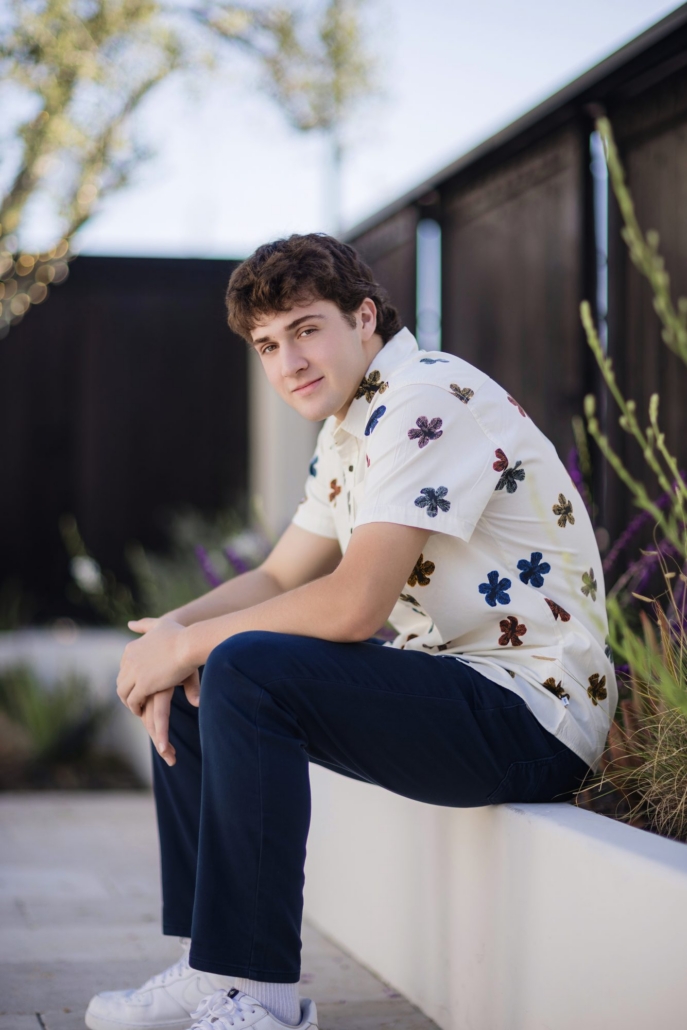 Senior guy in golden-hour light beside lavender and palms during his San Clemente session