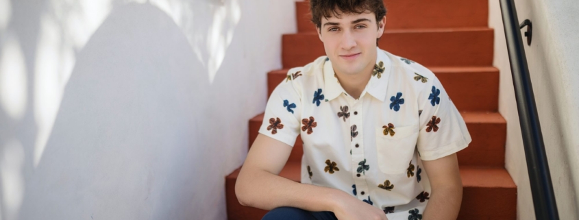 Senior guy in a floral shirt sitting on a terracotta Spanish staircase in San Clemente