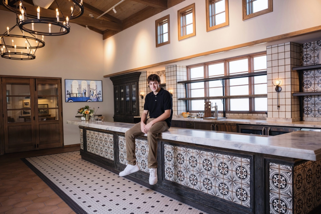 Editorial senior portrait of a guy on a Spanish-tile bar with iron chandeliers in San Clemente