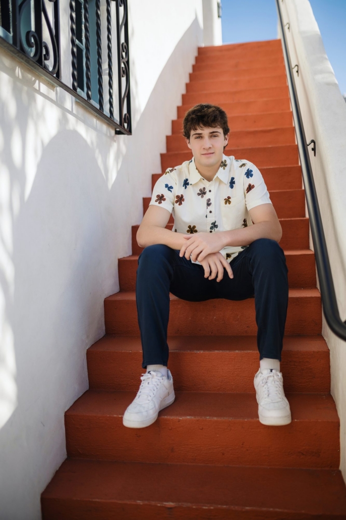 JSerra senior guy on red terracotta steps with wrought-iron railing in San Clemente