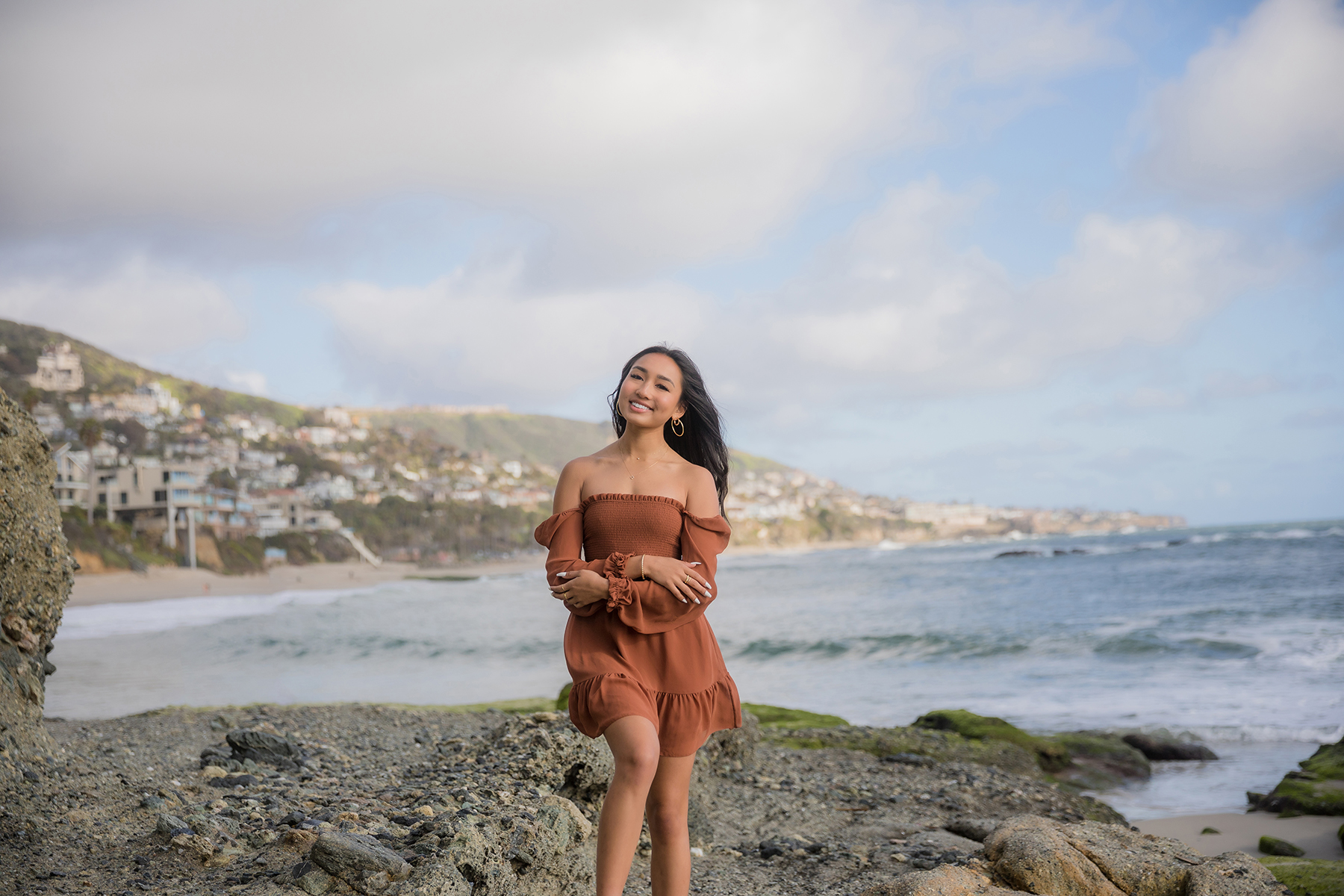 High school senior in a soft neutral outfit posing at golden hour on the Orange County coa
